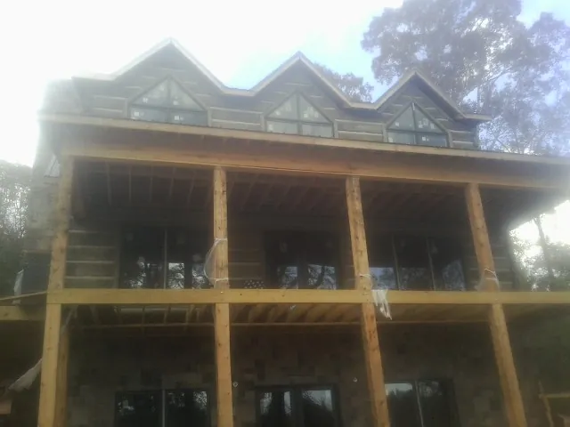 Dormers and porch framing on a large log home under construction — Roof Coating work by our crew in Echo