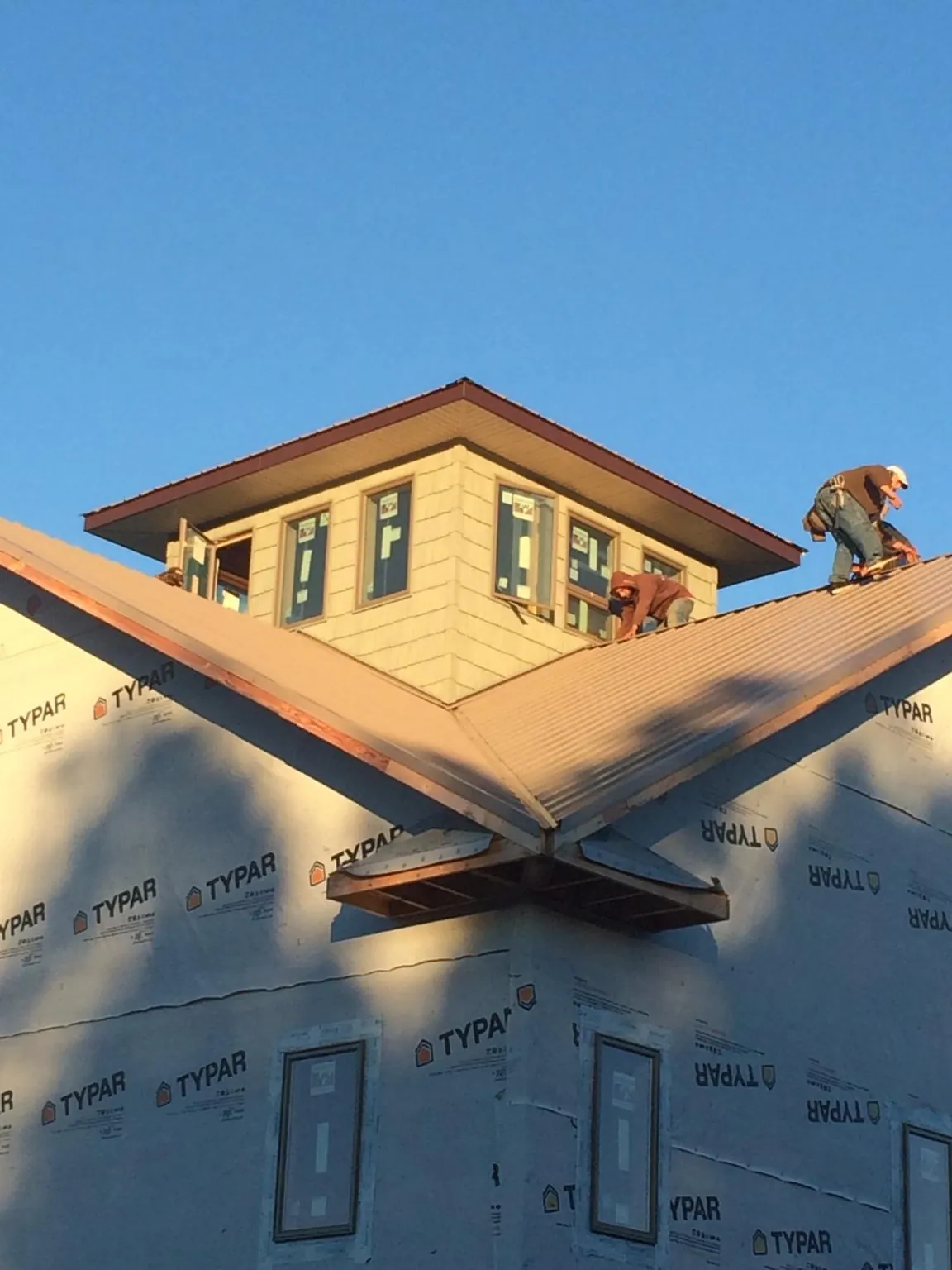 Roofers working around a rooftop cupola on a new metal roof at sunset — Roof Waterproofing in Echo by Roofing Brothers